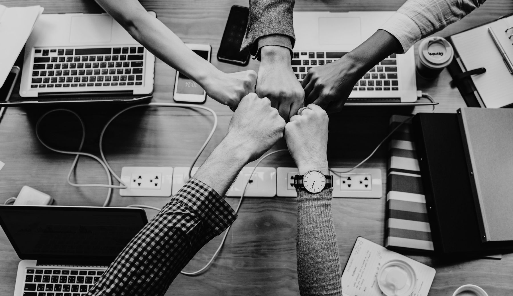 Hands meeting over laptops and office documents